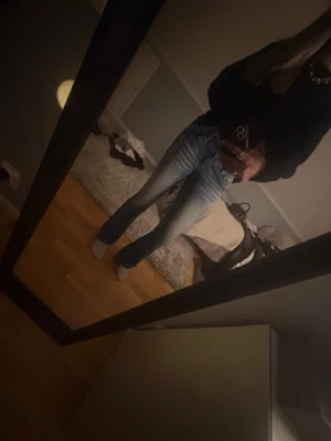Blå bootcut jeans från Vanity - Säljer ett par blå bootcut jeans från Vanity med slitningar och ljusa tvättade detaljer på låren och  låg midja. Nitar och annan dekoration på fram och bakfickorna. 