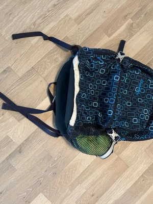 Bergans ryggsäck - Säljer en snygg blå ryggsäck från Bergans med geometriskt mönster i turkost. Ryggsäcken har flera justerbara remmar, meshficka på sidan och smarta spännen. Perfekt för dig som gillar att vara aktiv och vill ha en cool och praktisk väska.