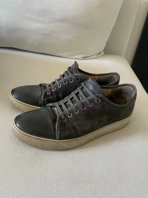 Gråa Lanvins - Snygga svarta sneakers med lågt skaft, ovandel i mocka och tåparti i slätt läder. Skorna har svarta skosnören och vit sula med diskret rand. Perfekta för en clean och stilren look.