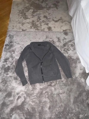 Mörkgrå ziptröja från Massimo dutti  - Snygg mörkgrå ziptröja med hög krage och hel dragkedja framtill. Tröjan har två fickor på sidorna och är tillverkad i ett mjukt, stickat material. Perfekt för lager på lager och enkel att matcha med olika outfits.