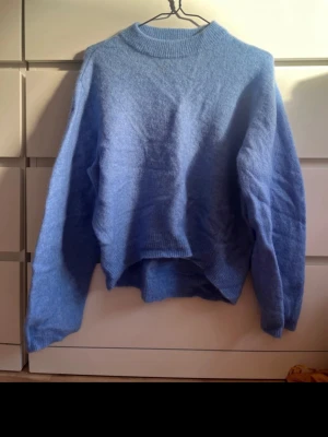 Blå stickad tröja Second Female - Mysig blå stickad tröja från Second Female i storlek XS. Tröjan har rund halsringning, ribbade muddar och en avslappnad passform. Perfekt för lager på lager och ger en soft vibe till din outfit.