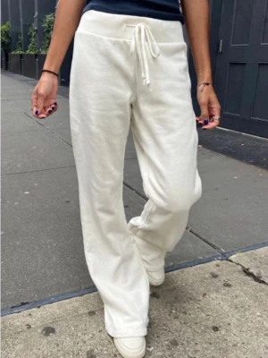 Yoga pants - Säljer ett par vita mjukisbyxor med bred resår i midjan och dragsko. De är från Brandy Melville och i modellen Hilary yoga pants. Byxorna har utsvängda ben och är gjorda i ett mjukt och bekvämt material, perfekt för chill dagar. Passar dig som gillar en avslappnad och enkel stil. Onesize men passar S/M. Liten fläck (se bild 3) men syns inte när man har på sig dem.