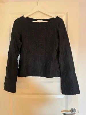 Svart långärmad topp från Bubbleroom  - Säljer en svart långärmad topp från Bubbleroom med diskret strukturmönster i tyget. Toppen har en rak passform och något vidare ärmar, vilket ger en cool och avslappnad look. Perfekt att styla med jeans eller kjol.