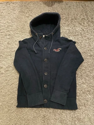 Mörkblå hoodie från Hollister - Säljer denna rikigt feta Hollister hoodien i storlek M men kan också passa S  den har inga defekter och är i gott skick. Den är dessutom sällsynt! 
