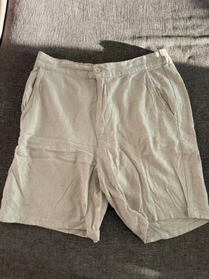 Beige linneshorts från Grunt - Snygga beige shorts från Grunt i luftig linnemix. De har normal passform, sidofickor och stängs med knapp och dragkedja. Perfekta för varma dagar och enkel att matcha med olika toppar.