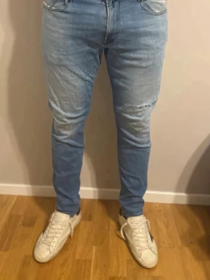 Ljusblå slim fit jeans-way Nudie Jeans - Säljer ett par ljusblå jeans från replay Jeans med slitningar på låren och knä och klassiska sopade bakfickor. Jeansen har normal midja, dragkedjegyl yourselves och är tillverkade i bomull. Perfekta för en avslappnad och trendig look.