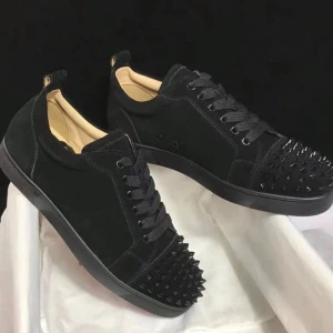 Svarta sneakers med nitar - Säljer ett par svarta sneakers från Christian Louboutin med coola svarta nitar på tån. Skorna har en låg profil, svarta skosnören och en stilren design i mocka och läder. Perfekta för dig som vill sticka ut med din stil.