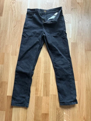 Svarta raka jeans från Lee 12-13 år - Säljer ett par svarta jeans från Lee med rak passform och klassisk femficksdesign. Jeansen har dragkedjegylf och bälteshällor. Materialet är mjukt och stretchigt för extra komfort. Perfekta för en avslappnad och stilren look.