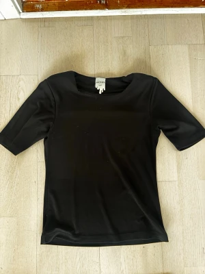 Svart topp från Monki - En enkel svart topp från Monki med rund halsringning och korta ärmar. Bekväm passform. Perfekt att styla till olika outfits.🖤