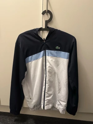 Lacoste tracksuit - Snygg tracksuit från lacoste, inga fläckar eller liknande men en defekt på dragkedjan vid byxbenet. Går att fixa enkelt. (se bild)