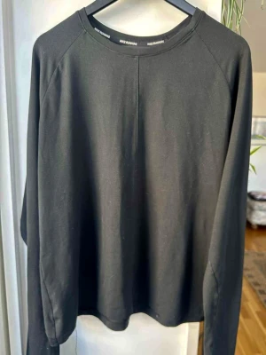 Svart långärmad tröja Nike Running - En stilren svart långärmad tröja från Nike Running med rund halsringning och rak passform. Tillverkad i mjukt och stretchigt material som passar perfekt till både träning och chill. Diskret Nike Running-tryck på insidan av kragen.
