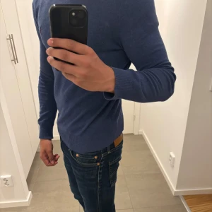 Blå stickad tröja från Polo Ralph Lauren - Säljer en klassisk blå stickad tröja från Polo Ralph Lauren. Tröjan har rund halsringning och långa ärmar, perfekt för lager-på-lager eller som den är. Enkel och stilren design som passar till mycket.