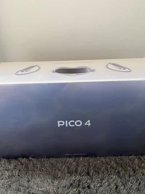 Pico 4 VR-headset med kontroller - Pico 4 VR-headset i vit plast med matchande kontroller. Snygg och modern design med justerbart huvudband och stora linser för bred synvinkel. Perfekt för gaming och VR-upplevelser, levereras i originalkartong.