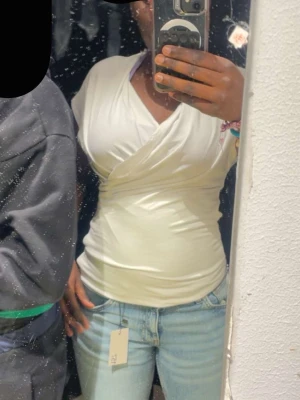 Vit omlottopp med v-ringning🤍 - Snygg vit omlottopp med v-ringning och tight passform. Toppen har korta ärmar och är perfekt att styla med jeans.🤍