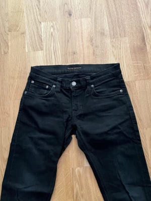 Svart Nudie Jeans - Klassiska svarta Nudie jeans till salu, Storlek Waist 27 / Lenght 30. Plagget är i mycket bra skick, inga skador. Hör av dig vid intresse/frågor. PRIS KAN DISKUTERAS!