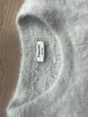 Vit  fluffig stickad tröja Kappahl - Vit stickad tröja från Kappahl i storlek 146 till 152. Tröjan har en fluffig och mjuk textur, rund halsringning och lång ärm. Perfekt för kalla dagar när du vill ha något extra gosigt på dig.tröjan original prick är 350