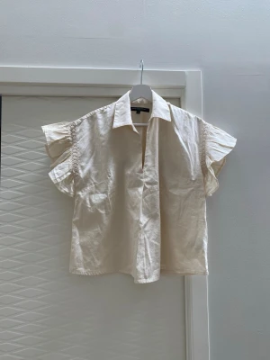 Krämvit blus med volangärm - Snygg krämvit blus med volangärmar. Från French Collection i nyskick 