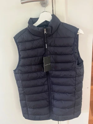 Mörkblå väst - Snygg marinblå väst från Valmont Wear. Helt oanvänd då den tyvärr är för liten för mig. Storlek L men passar som en M i passformen. 