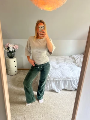 Gröna velour mjukisbyxor med dragsko - Mörkgröna mjukisbyxor i mjuk velour med raka ben och dragsko i midjan. Perfekta för en avslappnad och chill stil. Byxorna har en klassisk passform och är riktigt sköna att ha på sig.