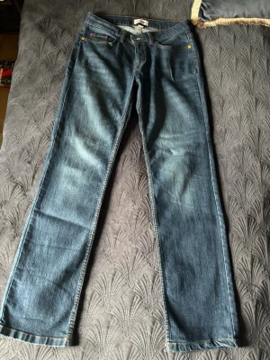 Blå raka jeans med klassisk tvätt - Snygga blå jeans med rak passform och klassisk tvätt. Jeansen har fem fickor, guldfärgade nitar och kontrastsömmar. Tillverkade i denim med en lätt sliten look. Perfekta för en avslappnad stil.