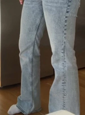Ljusblå bootcut jeans - Säljer ett par ljusblå bootcut jeans med låg midja. Jeansen är tillverkade i denim med lite stretch och är från H&M i storlek 36. 