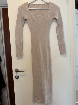 Beige ribbad figurnära långklänning - Långärmad beige ribbad klänning med figurnära passform. Inga fler bilder.