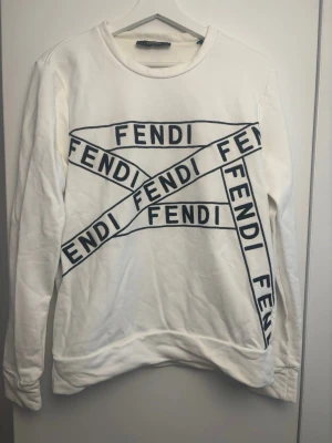 Vit sweatshirt från Fendi - Vit sweatshirt från Fendi med svart logotyptryck i flera riktningar över hela framsidan.