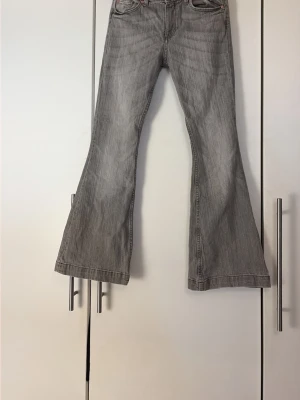 Grå bootcut jeans från H&M - Snygga grå bootcut jeans med klassisk femficksdesign och markerade sömmar. Baktill finns fickor med lock och knappdetaljer. Jeansen har en lätt utsvängd passform och är tillverkade i denim med diskret tvättad look.