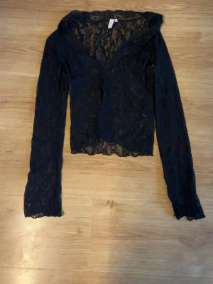 Svart spetsblus från Nelly - Snygg svart långärmad blus från Nelly i transparent spetsmaterial. Blusen har v-ringning och är figurnära med fina spetsdetaljer över hela plagget. Perfekt för dig som vill ha en trendig och elegant topp. Aldrig använd bara provad! 