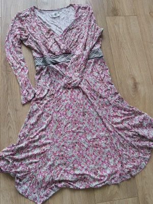 Blommig klänning från Container - Söt långärmad boho-inspirerad klänning från Container med livet i omlott. Perfekt för dig som gillar romantiska och feminina detaljer.