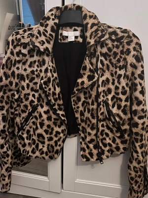 Leopardmönstrad skinnjacka H&M - Snygg leopardmönstrad skinnjacka från H&M med kort, figurnära passform. Jackan har bred krage, två snedställda dragkedjefickor och coola detaljer i svart. Perfekt för dig som vill sticka ut och addera edge till din outfit. Storlek 40 men passar mig som ofta bär 34/36. Pris kan diskuteras 
