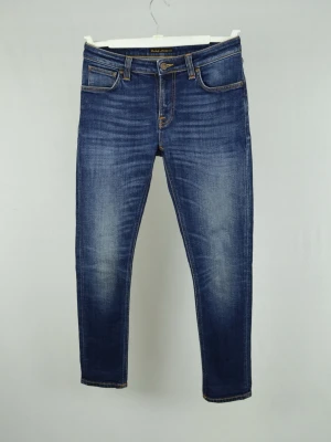 Nudie Jeans  - NUDIE JEANS Storlek : 31/30 Modell : Skinny Lin Mått : A = 39CM - B = 101CM Användning : Jeansen är i ett väldigt fint skick utan defekter Nypris : Cirka 2000SEK Modellen på bilden : 182CM och väger 78KG