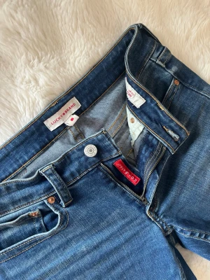 Blå bootcut jeans från lucky brand usa  - Säljer ett par klassiska blå bootcut jeans med snygga fickdetaljer bak och kontrastsömmar. Köpta i usa från lucky brand. Jeansen har normalhög midja och är tillverkade i ett stretchigt denimtyg som sitter skönt. Använda tre gånger. Mått finns med på bilden de är märkta 4/27 R. Passar mig bra med storlek m och det finns även plats utan att de sitter löst. 