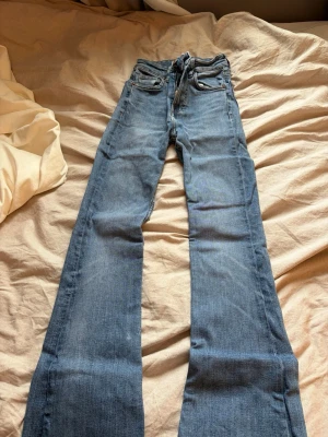 Blå bootcut jeans från Zara - Säljer ett par blå bootcut jeans från Zara med klassisk femficksmodell och dragkedja. Jeansen har en snygg tvättad look och är tillverkade i denim med lätt stretch. 