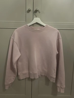 Ljuslila sweatshirt från Gina Tricot - En stilren ljusrosa sweatshirt från Gina Tricot, kollektionen Basically Basics. Tröjan har rund halsringning, ribbade muddar vid ärmslut och nederkant samt en relaxed fit. 