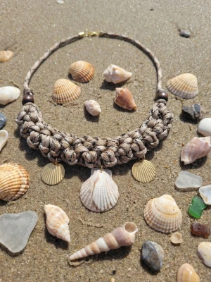 Makramé halsband med snäckor - Unikt handgjort halsband i makramé med tjockt flätat band i beige och bruna toner. Smycket är dekorerat med tre snäckor och två guldfärgade metallbrickor som hängande detaljer. Perfekt för en bohemisk strandlook och ger riktiga sommarvibbar. Snäckhänget är gjort i Polymerclay. Fäste bak.  Tot längd mönstret ca 22 cm. Hela ca 53 cm