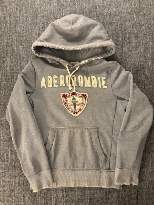 Abercrombie & fitch hoodie  - Eftertraktad Abercrombie & Fitch hoodie med sliten/vintage-inspirerad design. Riktigt snygg look och bra passform. Observera att det finns en defekt vid ärmen där den är extra sliten (se bild).  I övrigt bra skick och fullt användbar – ger en ännu mer rå vintage-känsla.  Skriv vid intresse – bra pris pga defekten ✌️ Skickas inom 24h 📦