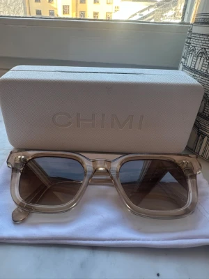 Beige solglasögon från Chimi (04) - Snygga solglasögon från Chimi med transparent beige båge och bruna tonade glas. Klassisk rektangulär form som passar till många stilar. Kommer med originalfodral och tygpåse.