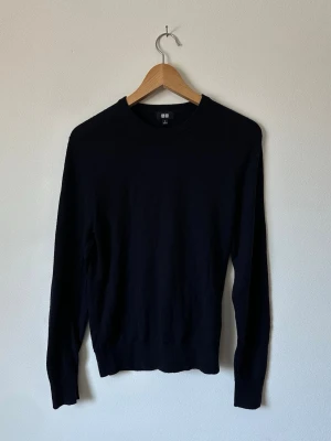 Svart tröja från Uniqlo - En stilren svart tröja från Uniqlo med rund halsringning och långa ärmar. Tröjan har en klassisk passform och är perfekt för lager-på-lager. Enkel design som funkar till många olika outfits. 8D17