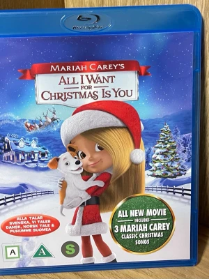 All I Want For Christmas Is You Blu-ray - Blu-ray med filmen 'Mariah Carey's All I Want For Christmas Is You'. Omslaget har en tecknad figur i tomteluva och röd julklänning som håller en hund. Filmen innehåller även tre klassiska julsånger av Mariah Carey. Svenskt tal finns.