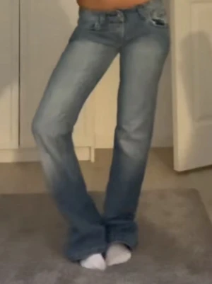 Bootcut jeans i ljusblå denim - Säljer ett par snygga bootcut jeans i ljusblå denim med klassisk femficksdesign och låg midja. Jeansen har lätt slitna detaljer och utsvängda ben, perfekta för en avslappnad och trendig look. Midjemått;36,5. Innerbenslängden:83