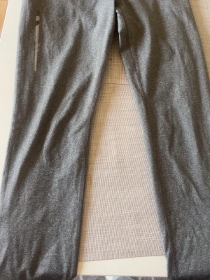 Grå leggings med dragkedjeficka - Snygga grå leggings i stretchigt material med en praktisk dragkedjeficka på sidan. Perfekta för dig som gillar en enkel och sportig stil. Tight passform och mjukt tyg som sitter skönt hela dagen.