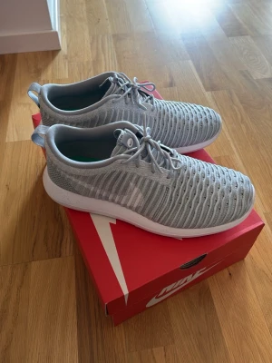 Nike grå låga sneakers.  - Aldrig använda. Snygga och lätta sneakers från Nike i ljusgrått meshmaterial med vita detaljer och vit sula. Skorna har en sportig look med snörning och låg profil, perfekt för dig som gillar stilrena och bekväma sneakers.