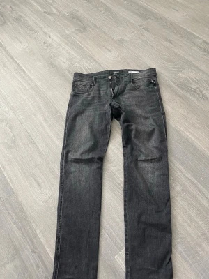 Replay svarta slim fit jeans - Säljer ett par svarta slim fit jeans från Replay med klassisk femficksmodell och snygga fades. Jeansen har normal midja och raka ben, perfekta för en stilren och avslappnad look. Materialet är mjukt denim med stretch för extra komfort.