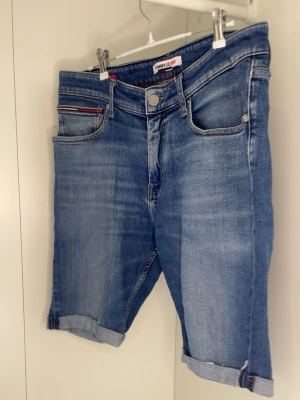 Tommy hilfiger shorts  -  Märke: Tommy Jeans (Tommy Hilfiger)  Typ: Jeansshorts  Färg/Tvätt: Mellanblå denim med lätt slitning/ljusare parti framtill  Detaljer:  Klassisk 5-ficksmodell  Liten broderad flagglogga på höger bakficka samt på den lilla myntfickan fram  Brun läderlapp (patch) i linningen bak med texten "Tommy Jeans"  Uppvikta/rullade i bensluten Pris kan diskuteras ( man får med org taggar och påse) 