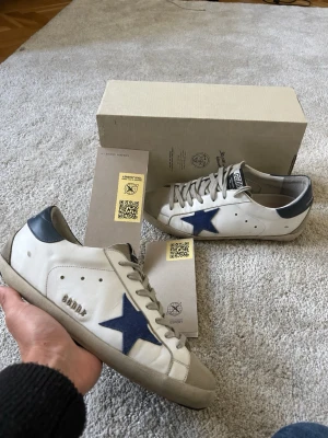 Golden Goose - Säljer ett par vita golden goose med blå stjärna. Storlek 43 och är normala i storleken, Qr-koden funkar!!. Skickar snabbt!🙌