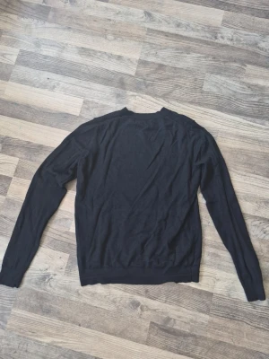 Svart stickad tröja från Lager  - Säljer en svart stickad tröja från lager 157 med rund halsringning och långa ärmar. Tröjan har en enkel design som är perfekt att matcha med olika outfits. Materialet är mjukt och bekvämt. Perfekt för kalla sommarkvällar men också när vintern närmar sig.