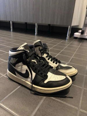 Air Jordan 1 mid - Air Jordan 1 mid sneakers i svart och vitt med klassisk vinge-logga på sidan och svart swoosh. Bra skick även fast dom är använda!! Beställda från nikes hemsida.