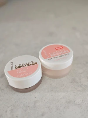 Catrice Under Eye Brightener duo - Två små burkar från Catrice: Under Eye Brightener Instant Awake och Under Eye Brightener Setting Powder. Båda har vita lock med rosa etikett och transparent burk. Perfekt för att ljusa upp och fixera under ögonen. Krämig och puderformel.  Endast testad. Säljer båda för 65kr!