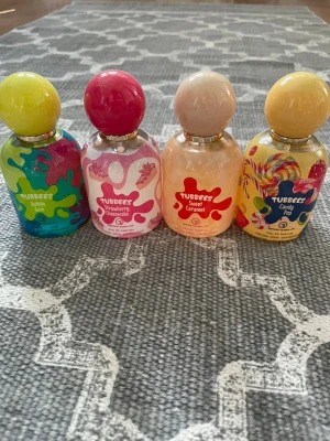 Grandeur TUBEES parfymset med fyra dofter - Fyra färgglada parfymer från TUBEES: Bubble Gum, Strawberry Cheesecake, Sweet Caramel och Candy Pop. Flaskorna är i glas med lekfulla etiketter och runda färgade lock. Doftnoterna är inspirerade av godis och desserter, perfekt för dig som gillar söta och unika parfymer. Knappt använda så i princip fulla flaskor. 50ml vardera